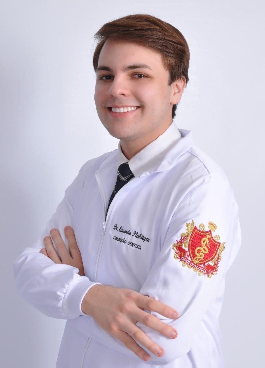Dr. Eduardo Plakitqen de jaleco, sorrindo, em retrato de estúdio